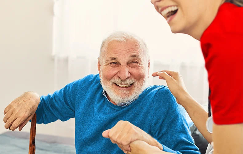 Happy elderly man receiving compassionate care from a caregiver, representing Geriatric Medicine Doctors, best geriatric doctors, senior care services, elder care, geriatric medicine, and family medicine and geriatrics.